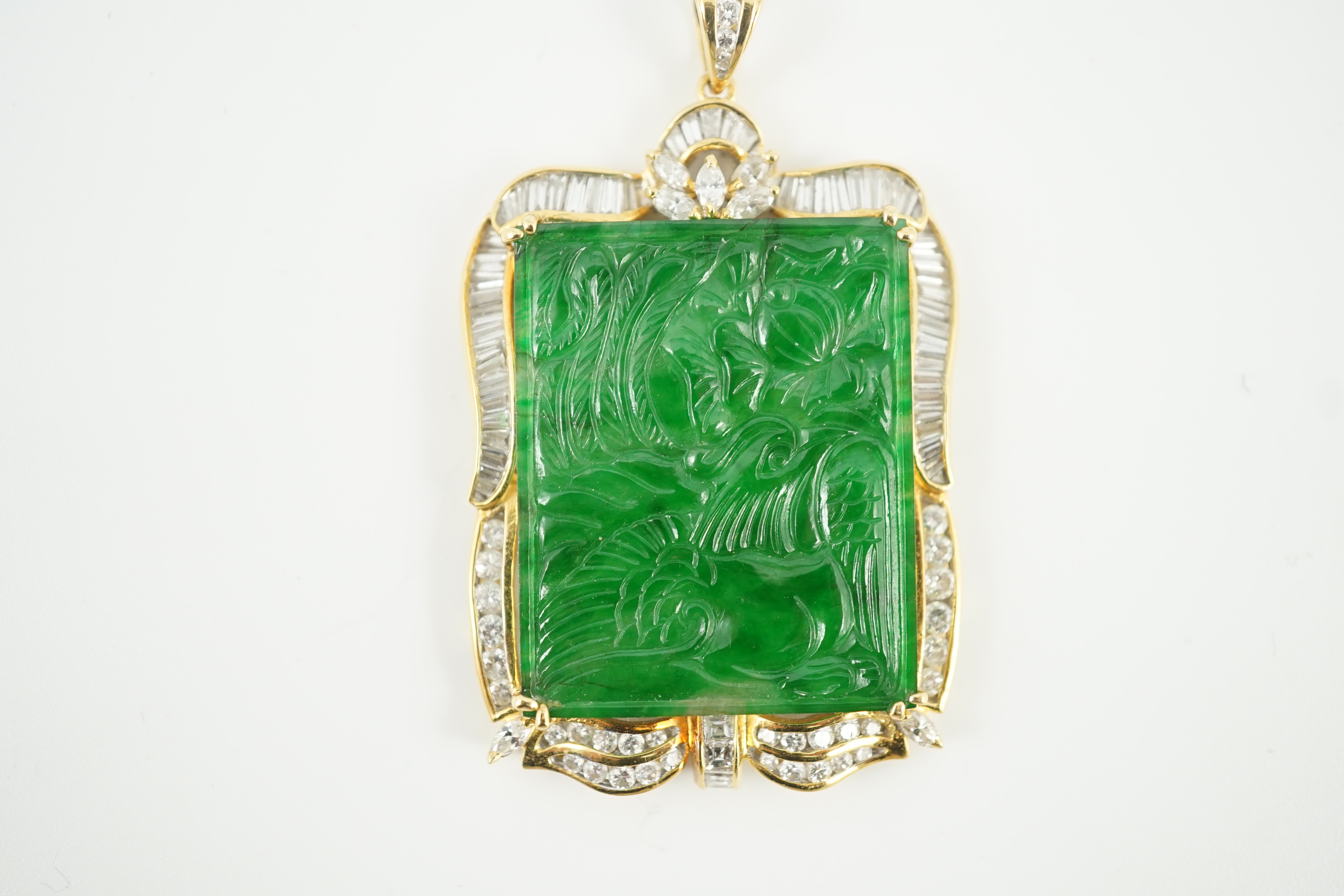 A late 20th century gold (tests as 18ct) mounted jade pendant, with round, marquise and trapeze cut diamond set border